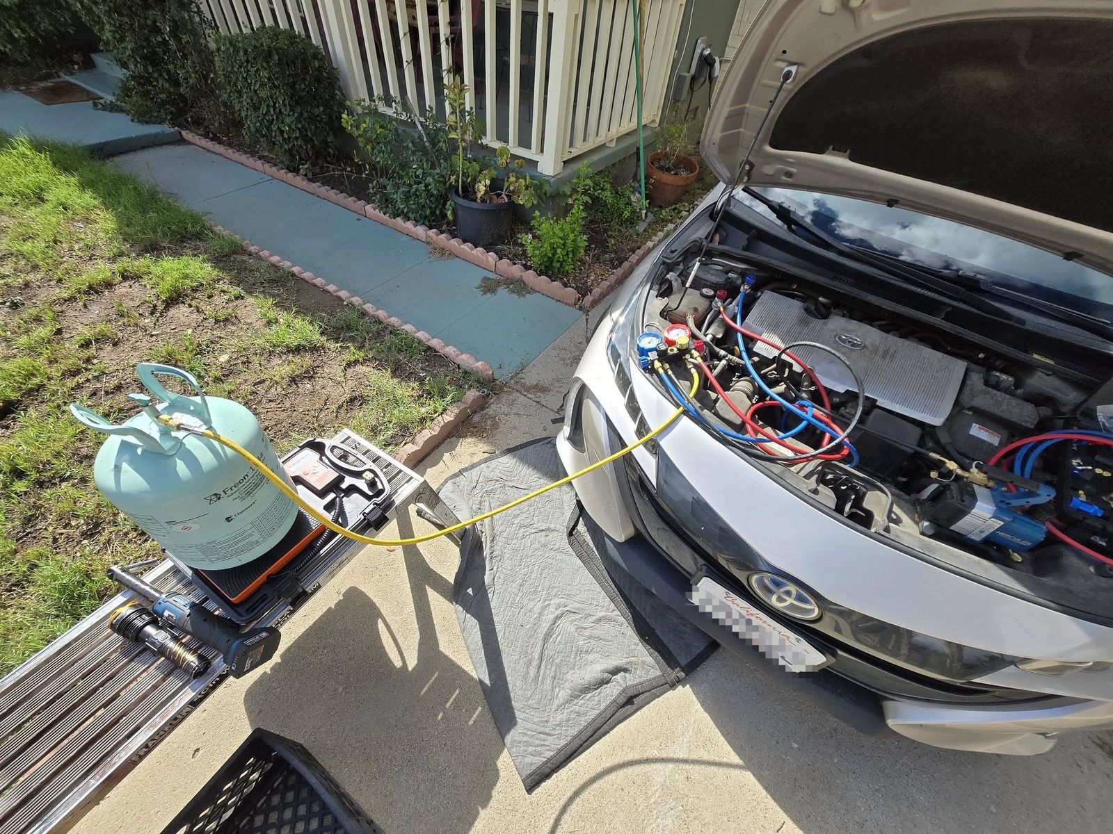A/C recharge on a 2017 Toyota Prius Prime in Ojai, refrigerant tank on a charging scale hooked to the car's A/C lines